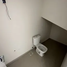 Foto de um canto de um banheiro mostrando um vaso sanitário branco.