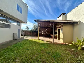 Vista externa de uma residência com jardim e área coberta.