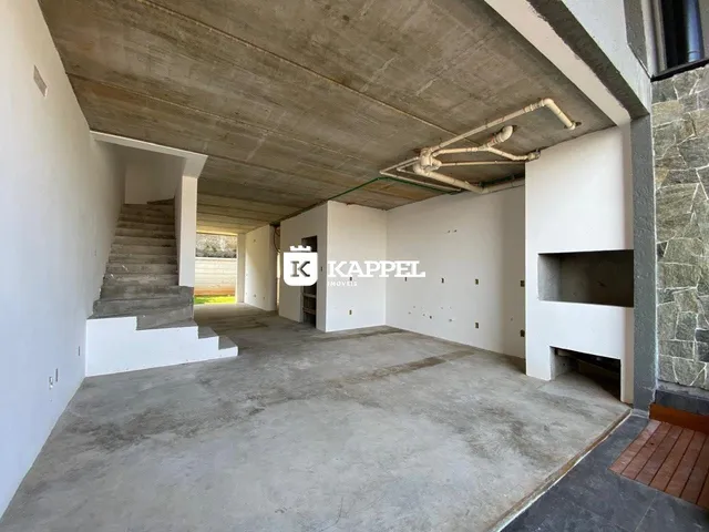 Vista interna de um espaço com piso de concreto e escadaria em uma residência.