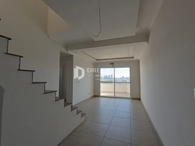 Vista de um corredor interno com escadaria e porta de vidro que dá para a vista.