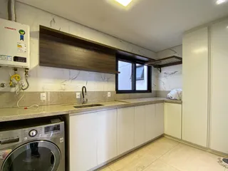 Cozinha moderna com bancadas claras e armários brancos.