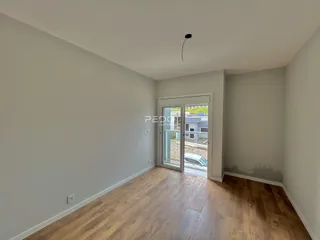 Espaço interno com piso de madeira e porta de vidro.