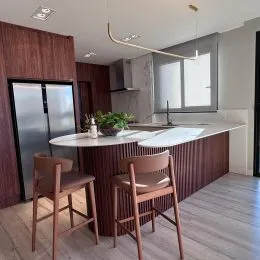 Foto de uma cozinha com bancada e cadeiras de madeira em um ambiente interno.
