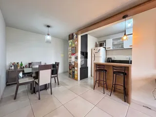 Ambiente aberto da sala de jantar e cozinha com piso de cerâmica.