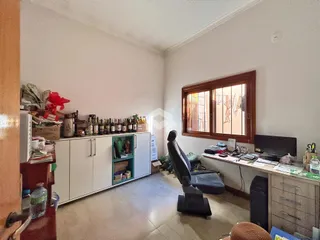 Interior de uma sala de estar com janelas de madeira e armários brancos.