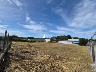 Vista aérea de um terreno aberto com vegetação seca e cercas no fundo.