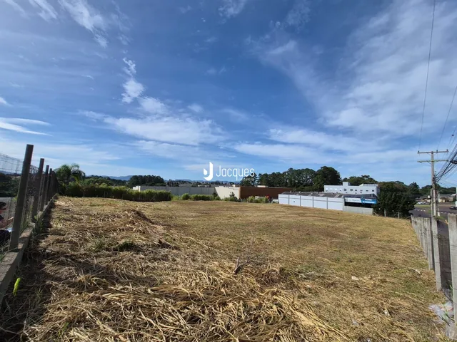 Vista aérea de um terreno aberto com vegetação seca e cercas no fundo.