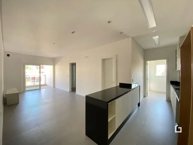 Ambiente interno de uma sala ampla com piso claro e paredes brancas.