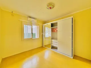 Sala de estar com paredes amarelas e piso de madeira clara.