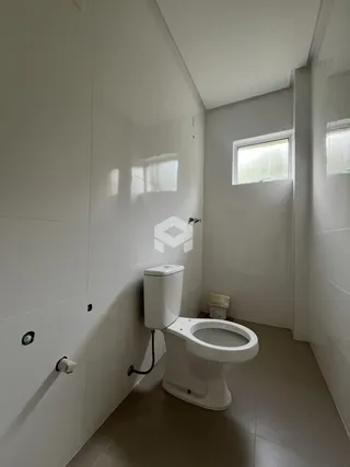 Interior de um banheiro moderno com azulejos brancos e vaso sanitário branco.