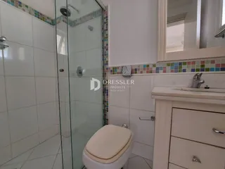 Foto de um banheiro com box de vidro e revestimento cerâmico.