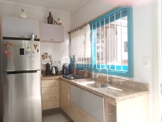 Cozinha com armários e janela com venezianas azuis.
