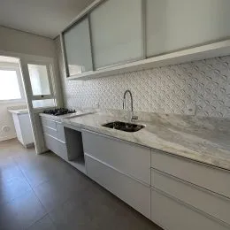 Cozinha com armários brancos e bancada clara.