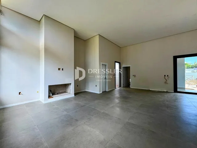 Ambiente interno amplo com paredes brancas e piso de concreto claro.