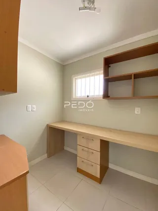 Interior de uma sala com paredes claras e móveis de madeira.