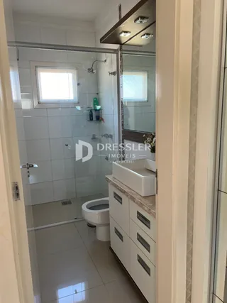 Foto de um banheiro com revestimento cerâmico e box de vidro.