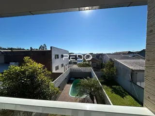 Vista externa de um quintal com vegetação e uma edificação no Brasil.