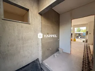 Foto de um interior com paredes de concreto aparente e uma abertura para uma área externa.