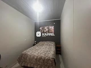 Quarto com cama coberta e cabeceira em um ambiente com paredes claras.
