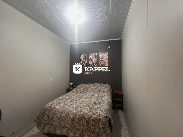 Quarto com cama coberta e cabeceira em um ambiente com paredes claras.
