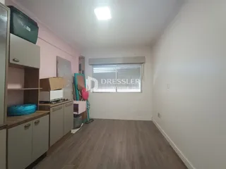 Quarto interno com piso de madeira e armários na parede esquerda.