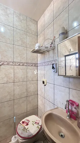 Foto de um banheiro com azulejos brancos e um vaso sanitário.
