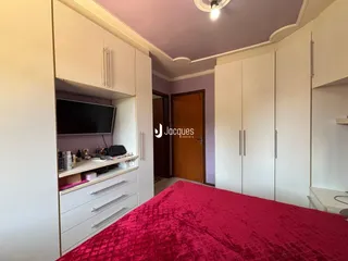 Quarto com armários embutidos e cama de cor vermelha.