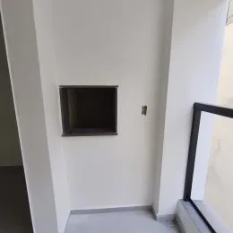 Vista de um corredor interno com paredes brancas e piso claro.