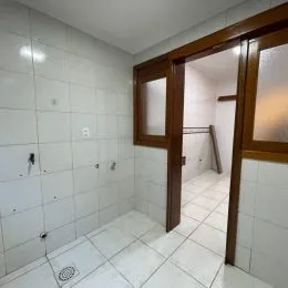 Foto de um corredor interno com piso de cerâmica branca.