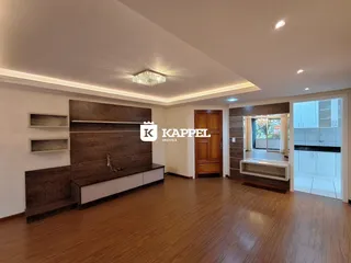 Sala de estar com painel de madeira e piso de madeira em um imóvel em Lajeado.