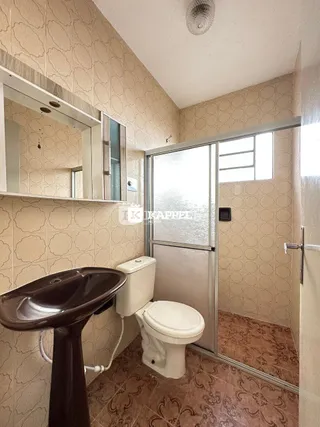 Foto interna de um banheiro com pia e vaso sanitário revestido de azulejos.