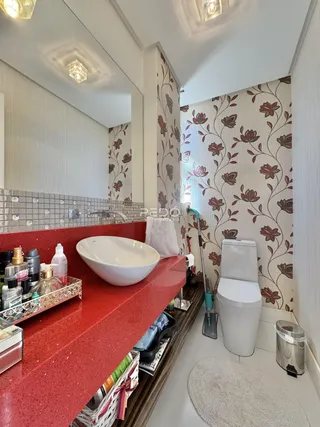 Banheiro com revestimento de parede floral e bancada vermelha.
