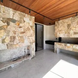 Interior com parede de pedra e teto de madeira em um ambiente residencial.