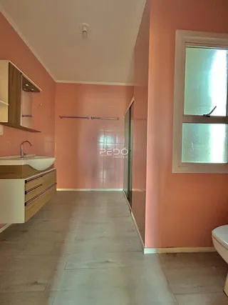 Vista de um corredor interno com paredes cor de rosa e piso claro.