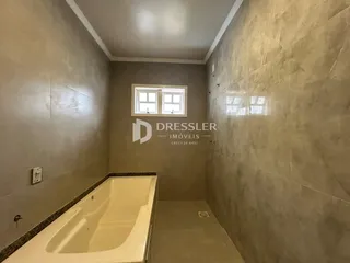Foto de um banheiro com banheira e paredes revestidas em tom neutro.