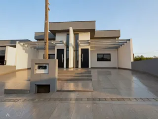 Fachada moderna de uma residência em Lajeado, Brasil, com revestimento branco e detalhes escuros.