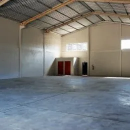 Foto de um espaço amplo com teto de metal ondulado e vigas expostas.