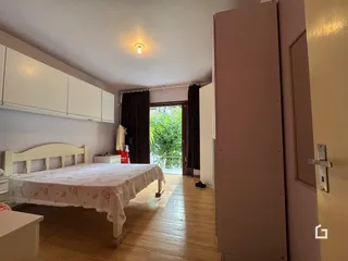 Quarto com piso de madeira e armários brancos.