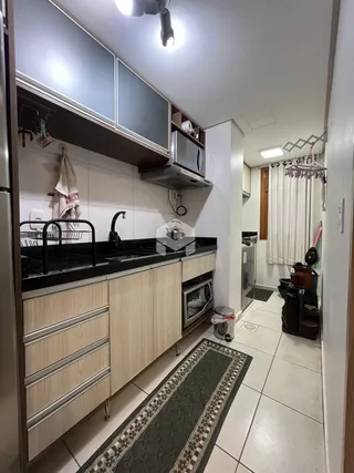 Cozinha com armários de madeira clara e bancadas escuras.