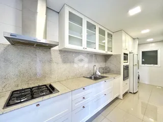 Cozinha moderna com armários brancos e bancada clara.