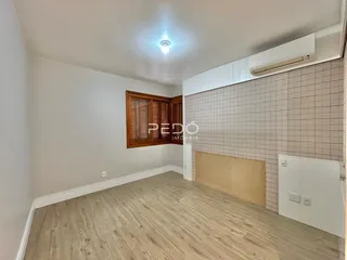 A sala apresenta piso de madeira clara e paredes brancas.