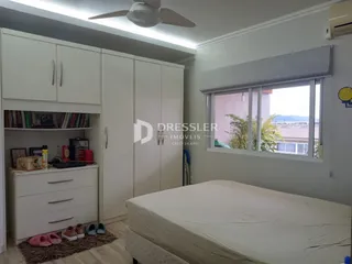 Quarto com armários brancos e cama em um ambiente claro.