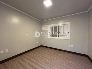 Ambiente interno de uma sala com piso de madeira e paredes claras.