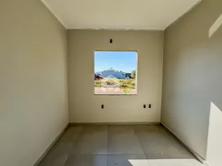 Vista interna de um ambiente com parede clara e piso de cerâmica.