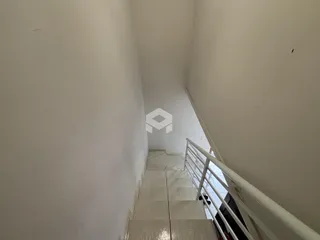 Vista de um corredor com escadaria em uma residência.