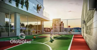 Campo de futebol gramado ao ar livre com cerca e estrutura moderna ao fundo.