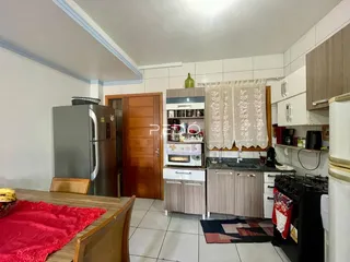Vista interna de uma cozinha com armários de madeira e eletrodomésticos de aço inoxidável.