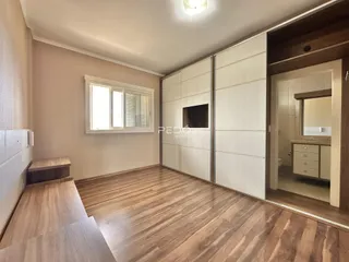 Sala de estar com piso de madeira e armários brancos.