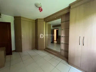 Quarto com armários em madeira e piso de cerâmica claro.