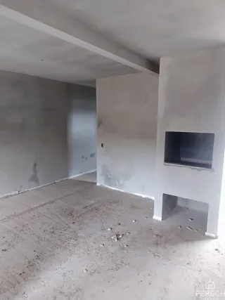 Interior de um cômodo com paredes brancas e piso de concreto aparente.